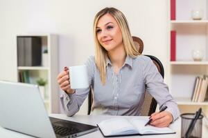 Geschäftsfrau Trinken Kaffee während Arbeiten im ihr Büro foto