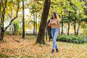 schön Frau Gehen im das Park und genießt im Herbst. foto