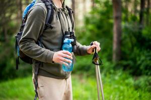 Bild von Mann halten Flasche von Wasser und Wandern foto