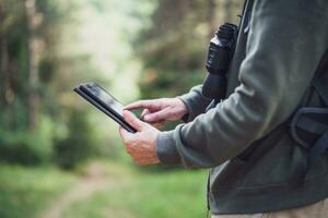 Bild von Wanderer mit Digital Tablette während Ausgaben Zeit im Natur foto
