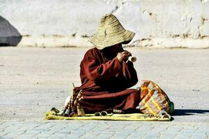 ein Mönch spielen ein Flöte im das Straße foto