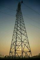 ein Silhouette von ein Elektrizität Turm beim Sonnenuntergang foto