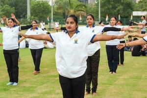 Neu Delhi, Indien, Juni 21, 2023 - - Gruppe Yoga Übung Session zum Menschen beim Yamuna Sport Komplex im Delhi auf International Yoga Tag, groß Gruppe von Erwachsene Teilnahme Yoga Klasse im Kricket Stadion foto