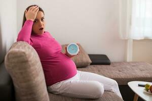 schwanger Frau im Panik halten Uhr. foto