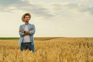 glücklich Farmer ist Stehen im seine wachsend Weizen Feld foto
