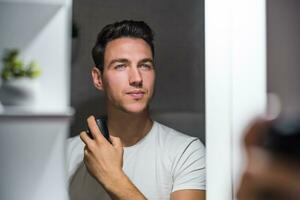 Mann mit Deodorant während suchen selbst im das Spiegel foto