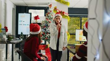 Unternehmen Mitarbeiter Mitglieder tragen Santa claus Hut genießen Weihnachten Geist Stimmung spielen vorgeben Spiel während Unterbrechung. Mitarbeiter haben Spaß tun Pantomime im Weihnachten schmücken Büro foto