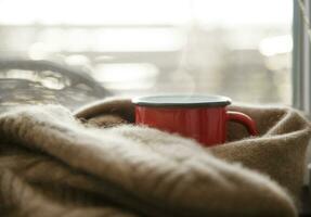 heiß trinken im ein rot Metall Becher eingewickelt im ein Kaschmir Schal auf ein kalt Tag foto