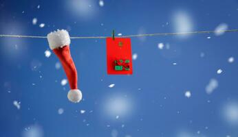 Santa Hut und rot Plastik Karte mit Neu Jahr Design hängend auf ein Zeichenfolge auf ein Blau Hintergrund foto