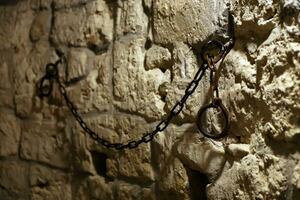 Sklaverei und Knechtschaft stark Stahl alt Fesseln auf Stein Mauer im Schloss Keller foto