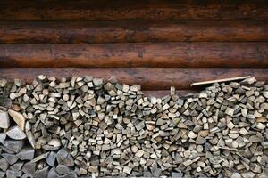Brennholz gestapelt in der Nähe von das hölzern Mauer von alt Hütte. viele gehackt Protokolle von Brennholz foto