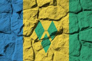 Heilige Vincent und das Grenadinen Flagge abgebildet im Farbe Farben auf alt Stein Mauer Nahaufnahme. texturiert Banner auf Felsen Mauer Hintergrund foto