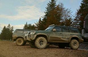 Automobil im ein Landschaft Landschaft mit ein Schlamm Straße. Offroad 4x4 suv Automobil mit ditry Körper nach Fahrt im schlammig Straße foto