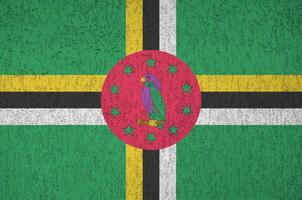 dominica-flagge in hellen farben auf alter reliefputzwand dargestellt. strukturierte Fahne auf rauem Hintergrund foto