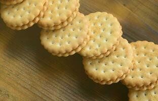 Ein runder Sandwichkeks mit Kokosfüllung liegt in großen Mengen auf einer braunen Holzoberfläche. Foto von essbaren Leckereien auf einem hölzernen Hintergrund mit Kopierraum