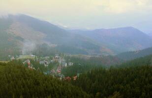 Morgen Aussicht von wohnhaft Bereich und Häuser um das Dragobrat Berg Spitzen im Karpaten Berge, Ukraine. wolkig und nebelig Landschaft um Drahobrat Spitzen foto