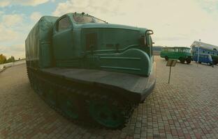 Foto eines russischen grünen Panzerwagens auf einer Gleiskette zwischen den Eisenbahnzügen. starke Verzerrung durch das Fisheye-Objektiv