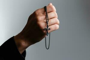 Mann betet mit ein Kreuz auf ein schwarz Hintergrund foto