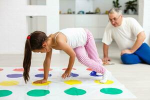 wenig Mädchen und Großvater abspielen Twister beim Zuhause foto