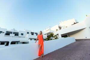 stilvoll jung attraktiv Frau gekleidet im ein orangefarben fotografiert im das Sommer- auf ein Hintergrund von Palme Bäume foto