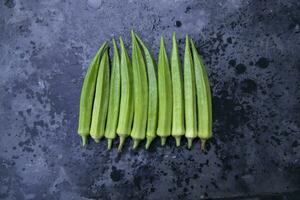 frisch organisch Gemüse Damen- Finger oder Okra auf das dunkel Beton Fußboden foto