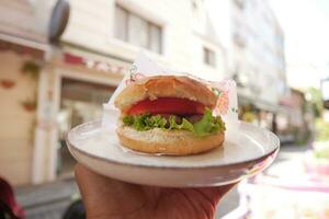 Cheeseburger mit Salat und Tomate auf ein Teller beim draussen foto