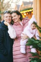 draussen Porträt von glücklich Familie mit bezaubernd Baby Mädchen beim Weihnachten Markt foto