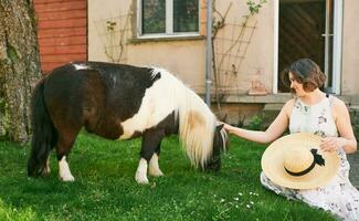 draussen Porträt von glücklich jung Frau spielen mit Pony, Bauernhof Ferien foto