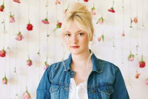 Studio Porträt von ziemlich jung Teenager 15 - - 16 Jahr alt Mädchen tragen Denim Jacke, posieren auf Weiß Hintergrund mit hängend Blumen, Schönheit und Mode Konzept foto