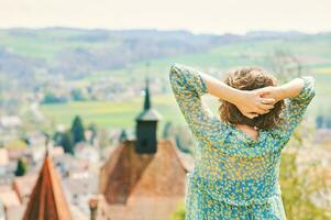 draussen Porträt von glücklich jung Frau Reise im Europa, Besuch alt Schloss, Bild nehmen im Schweiz, zurück Aussicht foto