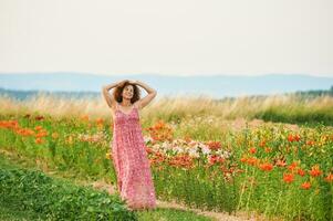 draussen Porträt von schön Mitte Alter Frau genießen nett suuny Abend im Landschaft, gelehnt auf Blume Zaun, tragen rot Kleid foto