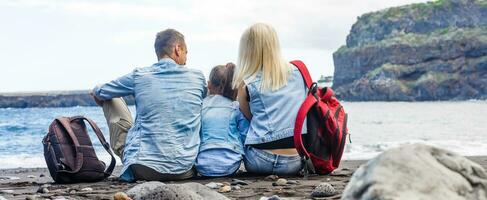 glücklich Familie Stehen auf das Strand auf das Dämmerung Zeit foto