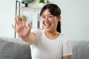 Porträt von jung asiatisch Frau tragen Auge Brille groß lächelnd und suchen beim Kamera mit Gefühl glücklich und positiv im Leben Zimmer beim heim, treffen, Video Konferenz. foto