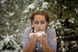 schön Mädchen weht Schnee aus ihr Hände. draussen Winter Porträt. foto