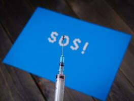 Spritze und SOS von Tabletten auf ein Blau Hintergrund. Verhütung von viral Krankheiten. foto