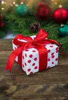 Geschenk Box Weiß rot mit Polka Punkte auf hölzern Bretter mit verschwommen Spielzeuge. Weihnachten, Neu Jahr. Vertikale. Kopieren Raum foto