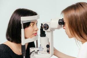 Frau haben Vision Prüfung auf ein Augenheilkunde Diagnose Vision testen Ausrüstung. Arzt tun Auge Prüfung mit nicht Kontakt Tonometer, Überprüfung Vision beim optisch Klinik foto