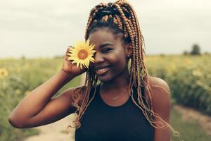 afrikanisch amerikanisch Mädchen im ein Feld von Gelb Blumen beim Sonnenuntergang foto