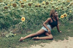 afrikanisch amerikanisch Mädchen im ein Feld von Gelb Blumen beim Sonnenuntergang foto