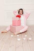 süß wenig Mädchen im Schlafanzug mit Süßigkeiten Sitzung auf das Fußboden foto