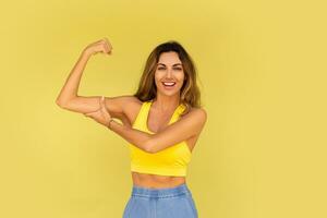 Studio Foto von ziemlich Brünette Frau im sportlich Outfit posieren auf Gelb Hintergrund.