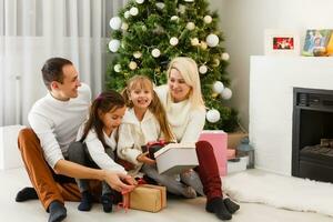 glücklich Familie Vater Mutter und Kinder Sitzung durch Kamin auf Weihnachten Vorabend foto