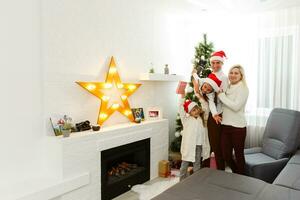 glücklich Familie Vater Mutter und Kinder Sitzung durch Kamin auf Weihnachten Vorabend foto