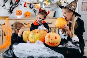 Familie hat lustige Zeit zu Hause. Mutter und Tochter werden einen Kürbis beißen - Halloween-Konzept foto