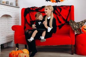 Frau und kleines Mädchen haben eine lustige Zeit auf dem roten Sofa. Emotion und Halloween-Konzept foto