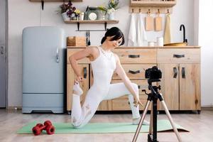 junge Frau, die Yoga praktiziert und ein Video mit ihrer Kamera macht foto