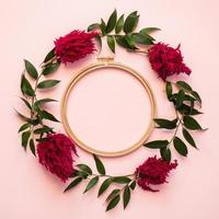 Nahaufnahme eines Kreises frischer Blumen und eines grünen Blattes liegen auf einem rosa Hintergrund - Kopienraum foto