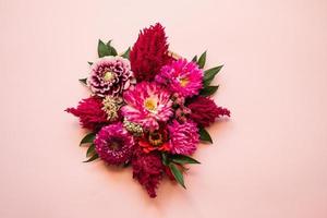 Strauß frischer Blumen in der Mitte eines rosa Hintergrundes foto