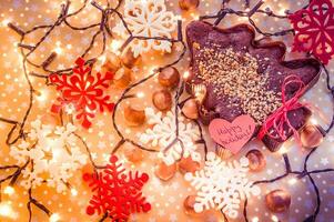 Lebkuchen Baum umgeben mit Weihnachten Beleuchtung und rot und Weiß Schneeflocken und glücklich Ferien Aufkleber foto