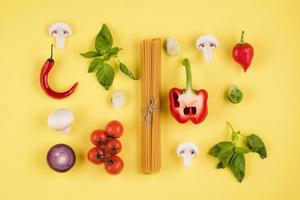 Konzept der italienischen Küche. auf gelbem Grund eine Reihe von Zutaten, Nudeln, Tomaten, Paprika, Pilzen, Basilikum foto